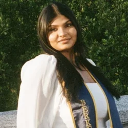 Sravya standing outside with graduation sash from UC Berkeley